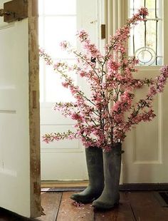 a vase filled with pink flowers sitting on top of a wooden table next to a doorway