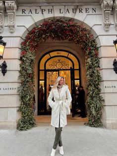 a woman standing in front of a large building with christmas decorations on the doors and windows