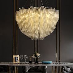 a chandelier hanging over a dining room table with two chairs and a vase