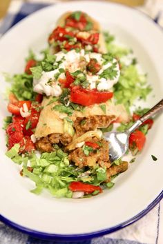 a white plate topped with meat and veggies on top of a bed of lettuce