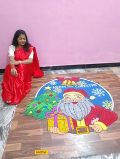 a woman sitting on the floor in front of a christmas tree with santa clause painted on it