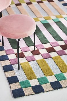 a pink chair sitting on top of a colorful rug