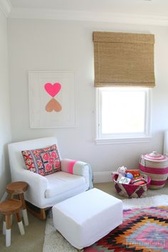 a child's room with white furniture and rugs on the floor, including a chair