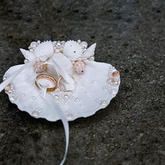 two wedding rings sitting on top of a white flower with pearls and pearls around it