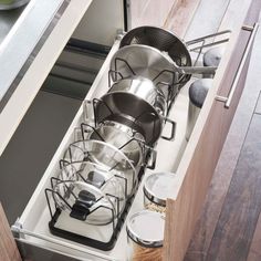 an open drawer with pots and pans on the bottom shelf in a modern kitchen