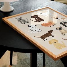 a wooden table topped with an art piece on top of a hard wood floor next to a lamp