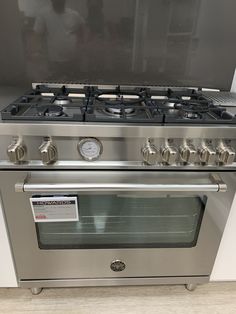 a stainless steel gas stove with four burners and two oven doors on each side