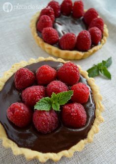 two pies with chocolate and raspberries on top