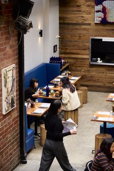 people sitting at desks in a restaurant with wood walls and blue booths on either side