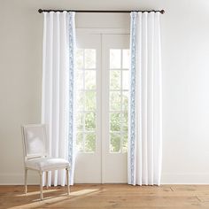 a white chair sitting in front of a window next to a wooden floor and wall