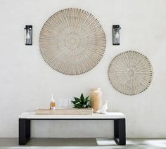 two circular wall hangings on the wall above a table with bottles and vases