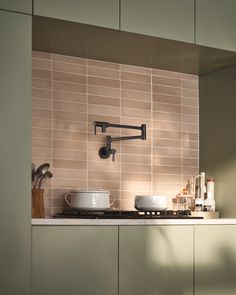 a stove top oven sitting under a faucet next to a wall mounted pot holder