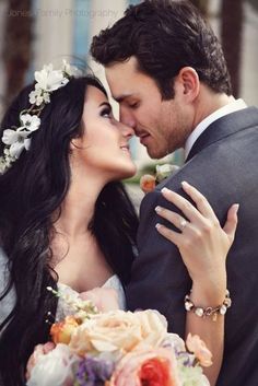 a bride and groom embracing each other in front of a building with flowers on it