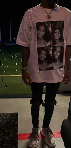 a man standing in front of a baseball field wearing a t - shirt with photos on it