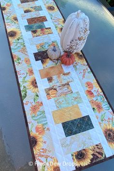 a quilted table runner with sunflowers and pumpkins on the top, along with an oven mitt