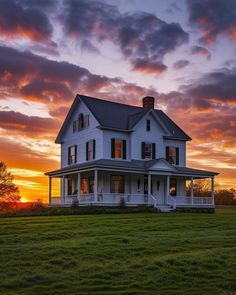 a large white house sitting on top of a lush green grass covered field at sunset