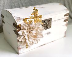 a white box with a flower on the front and gold trimmings around it