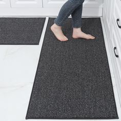 a woman standing on the floor in front of two black rugs with her bare feet sticking out