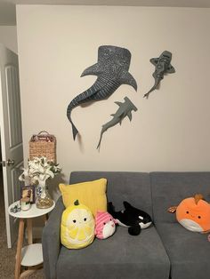 three stuffed animals sitting on the back of a couch in front of a wall mounted shark