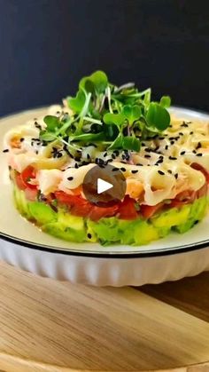 a white plate topped with a sandwich covered in veggies and sauce on top of a wooden table