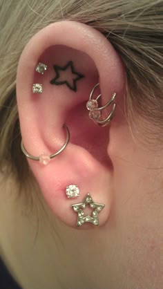 a person with three different ear piercings on their left and right ears, all in silver