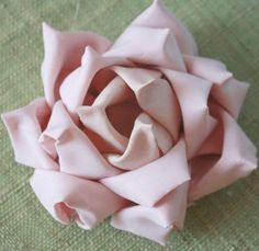 a pink flower sitting on top of a green cloth covered tablecloth with a knot in the center