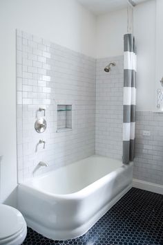 a white bathtub sitting next to a toilet in a bathroom under a shower curtain