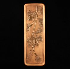 a gold bar with pine cones and needles on it's side, against a black background