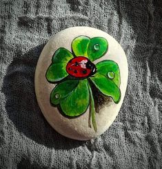 a painted rock with a ladybug sitting on it's leaf and water drops