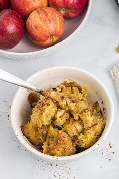 a bowl filled with food next to some apples