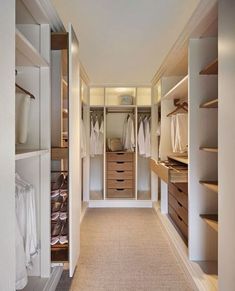 an image of a walk in closet with clothes on the shelves