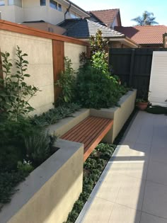 a wooden bench sitting in the middle of a garden next to a fence and building