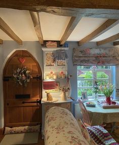 a living room filled with furniture next to a wooden table and window covered in flowers