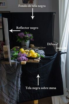 a black table topped with fruit and vegetables next to a white window covered in curtains