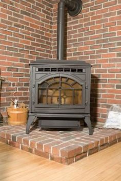 a wood burning stove sitting on top of a wooden floor next to a brick wall