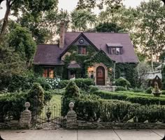 a house with ivy growing all over it's walls and roof, surrounded by hedges