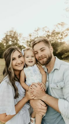 a man and woman holding a baby in their arms