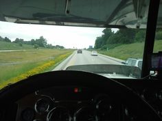 the view from inside a vehicle driving down a road with yellow flowers in the foreground