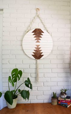 a wooden table topped with potted plants next to a wall hanging on a brick wall