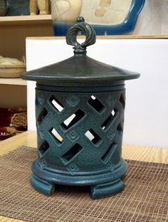 a green lantern sitting on top of a wooden table next to a vase and other items