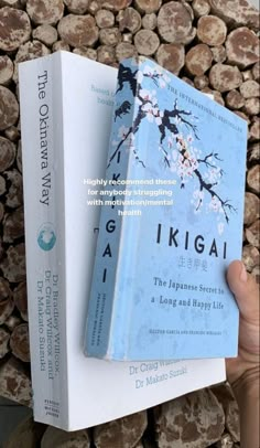 a person holding two books in front of stacked logs with the title, the japanese secret