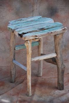 an old wooden table with two stools on the bottom and one chair up against it