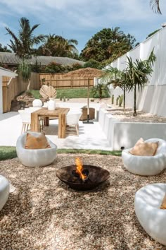 a fire pit surrounded by white chairs and tables