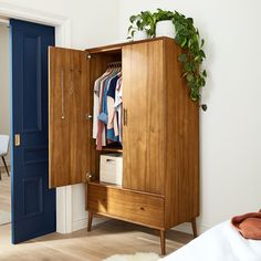 a wooden cabinet with clothes hanging on it's sides and a blue door in the background