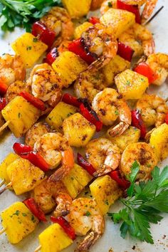 grilled shrimp and pineapple kabobs on a white plate with parsley