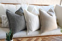 a white couch with four different colored pillows on it and a potted plant in the corner