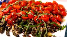 a white plate topped with lots of tomatoes and greens