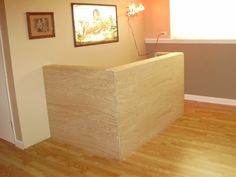 a wooden counter sitting in the middle of a room next to a wall with pictures on it