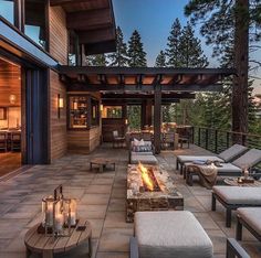 an outdoor living area with couches, tables and candles on the fire pit at dusk