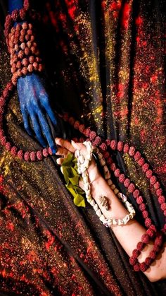 two hands with bracelets and beads on their wrists are shown in this artistic photograph